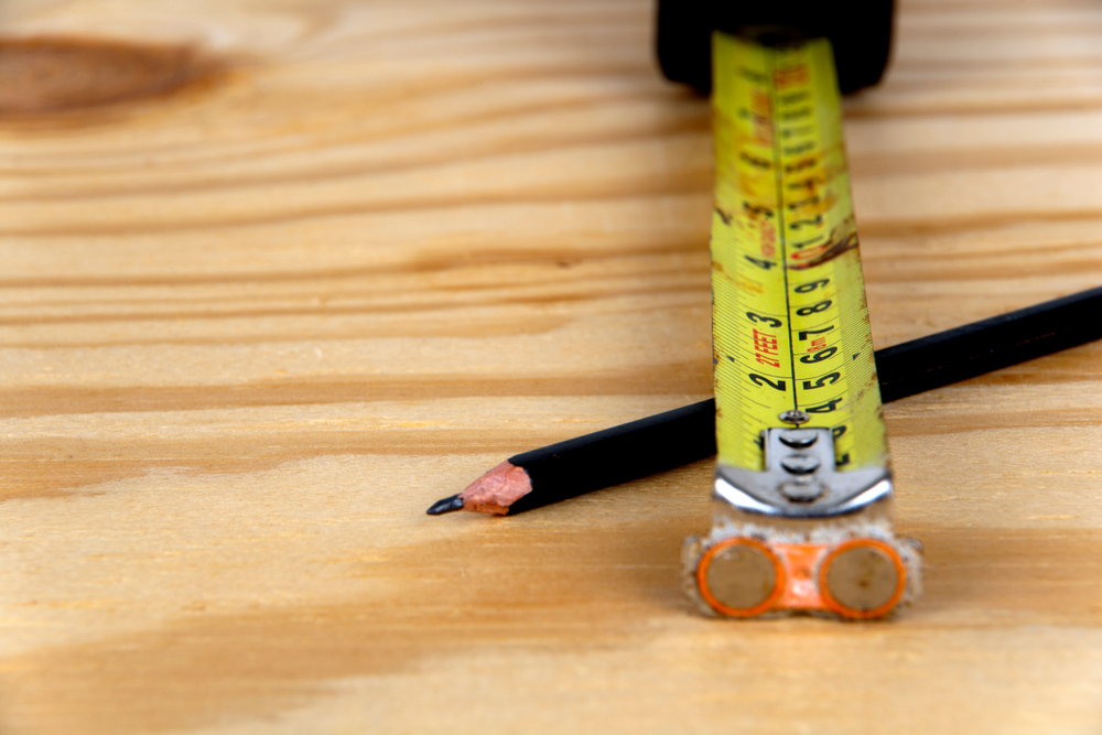 An Old Well Used Tape Measure And Pencil On A wood plank